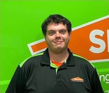 Male employee with dark hair in front of wall