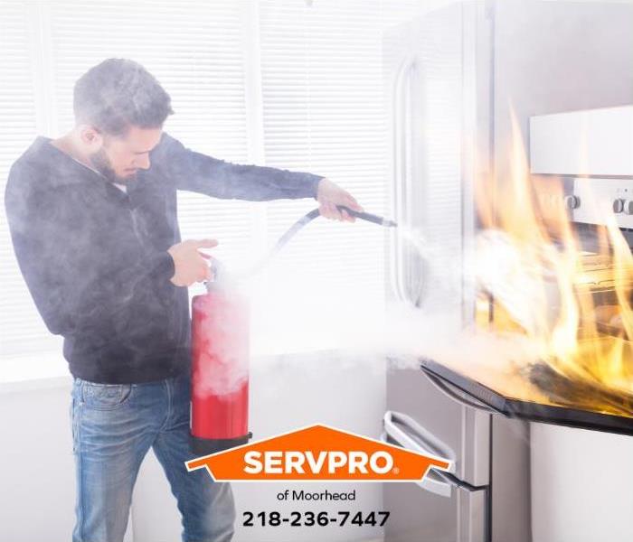 A person uses a fire extinguisher to put out a fire in an oven.